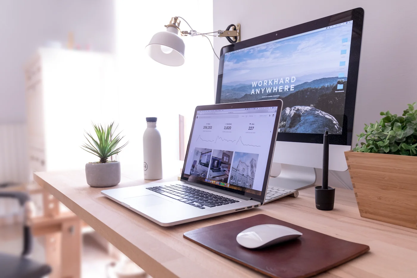 A tidy workspace with a laptop and large monitor