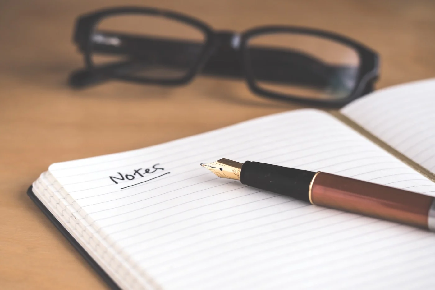 A fountain pen and glasses beside working notes