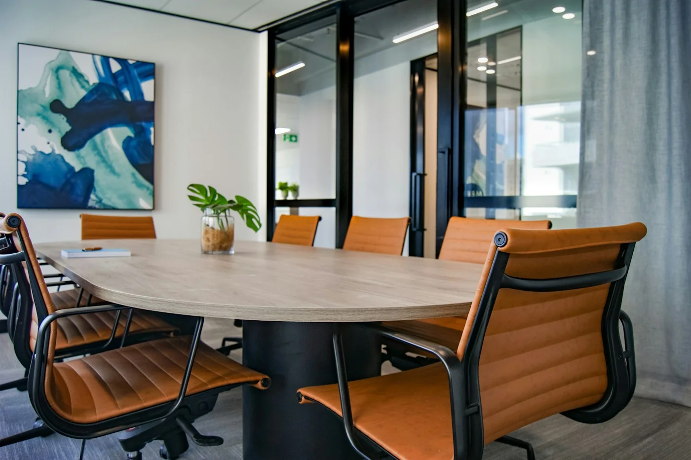 A bright meeting room with a wooden table and leather chairs
