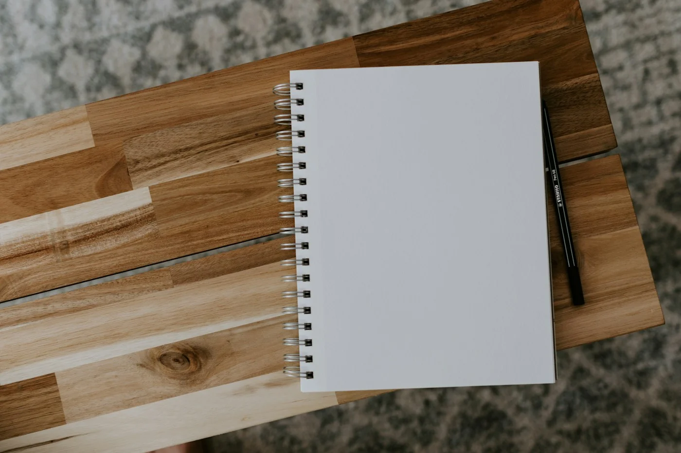 A notebook and pen on a tidy wooden desk